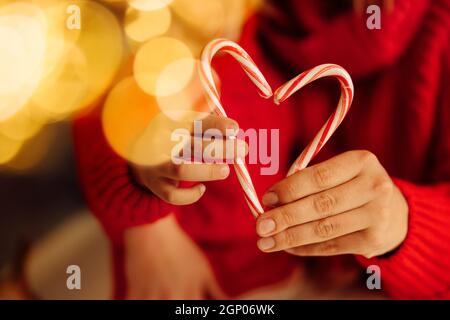 Gros plan de Cannes de bonbons en forme de coeur, qui fait mère et petit fils dans les chandails rouges.Concept de célébration du nouvel an et de Noël Banque D'Images