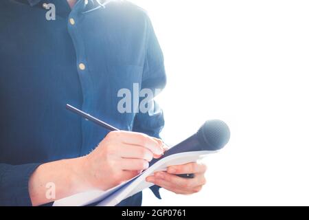 Cut-out d'un journaliste mâle dans un maillot bleu lors d'une conférence de presse qui est la prise de notes et la tenue d'un microphone Banque D'Images