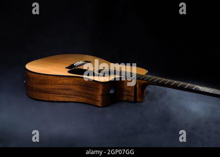 Guitare acoustique classique en jaune avec garde-pickguard noir sur isolé arrière-plan noir Banque D'Images