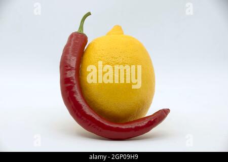 Citron jaune avec poivre rouge amer sur fond blanc. Banque D'Images