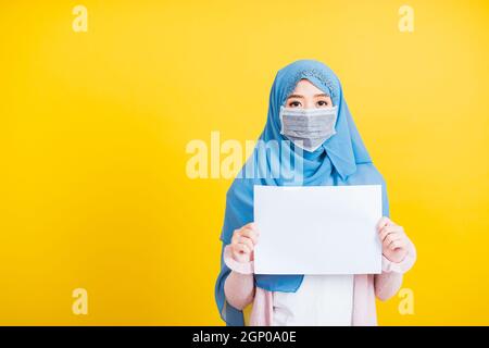 Arabe musulman asiatique, Portrait de la belle jeune femme religieuse porter voile hijab et masque de protection pour prévenir le coronavirus elle tient le livre blanc bl Banque D'Images