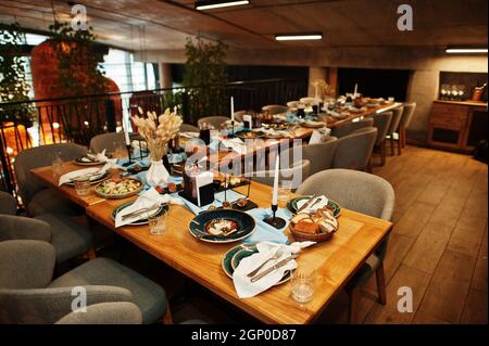 Tables joliment agentées avec nourriture, verres et appareils électroménagers au restaurant. Banque D'Images