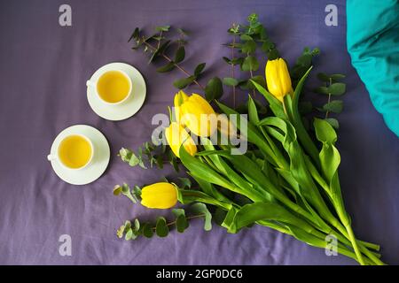 Tulipes jaunes et deux tasses de thé au lit, matin Banque D'Images