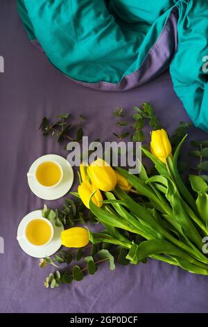 Tulipes jaunes et deux tasses de thé au lit, matin Banque D'Images