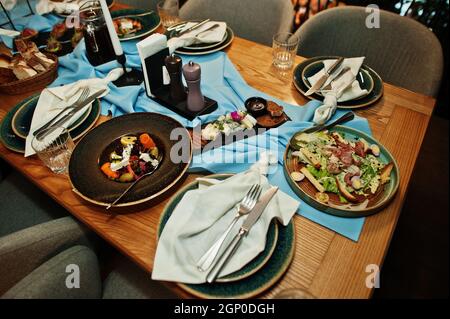 Tables joliment agentées avec nourriture, verres et appareils électroménagers au restaurant. Banque D'Images