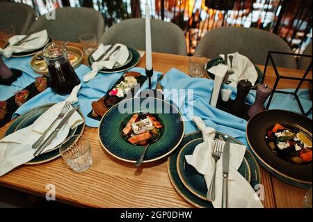 Tables joliment agentées avec nourriture, verres et appareils électroménagers au restaurant. Banque D'Images