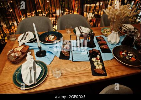 Tables joliment agentées avec nourriture, verres et appareils électroménagers au restaurant. Banque D'Images