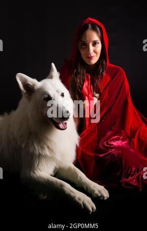 Femme portant une cagoule rouge posing in studio with her dog Banque D'Images