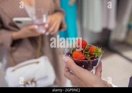 La fillette de cuisine tient un pot de dessert aux fruits et de fraises entre ses mains Banque D'Images