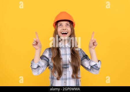 bonne jeune fille dans un casque et une chemise à carreaux pointant le doigt vers le haut, démontrez Banque D'Images