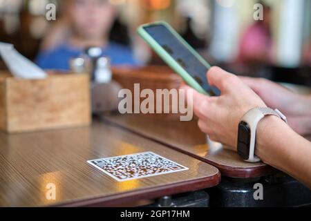 Gros plan sur la commande manuelle de repas par le client dans le restaurant tout en scannant le code qr avec le téléphone portable pour accéder au menu en ligne. Banque D'Images