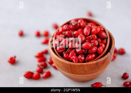 Plantes médicinales et herbes. Baies de hanches roses dans un bol en bois sur fond de béton avec espace de copie. Fruits secs pour tisanes et huiles essentielles Banque D'Images