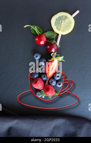 Fruits d'été, baies et menthe à la craie tasse de thé peinte avec paille sur fond noir avec toile. Alimentation conceptuelle saine, vitaminée, diététique. Vég Banque D'Images