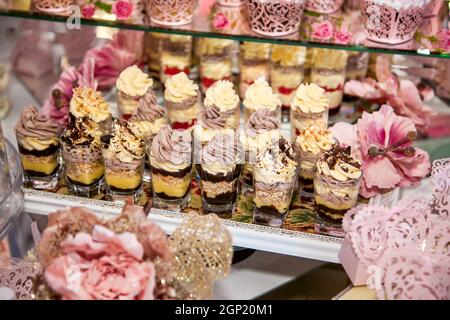 Délicieux desserts au bar à bonbons du mariage dans la zone du buffet : verres avec un dessert en couches avec chocolat, crème, noix, soufflé, crème fouettée. Banque D'Images