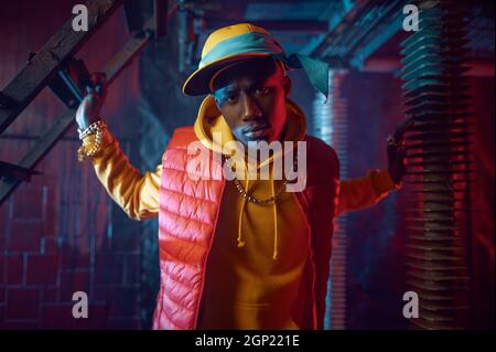 Elégant rappeur à capuchon jaune posé dans un studio de grunge avec une décoration souterraine fraîche. Hip-hop, chanteur de rap, performance de danse de saut Banque D'Images