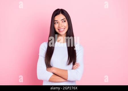 Photo portrait d'une fille avec des mains croisées dans une chemise bleue sourire heureux regardant vide espace isolé sur fond rose pastel Banque D'Images