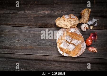 Pain de campagne avec morceaux de miettes, gousses d'ail et échalotes sèches françaises sur un panneau de bois de grange Banque D'Images