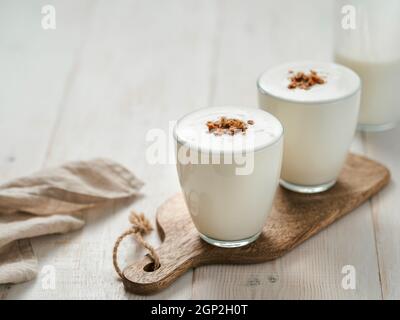 Kéfir, babeurre ou yaourt avec granola. Yaourt en verre sur fond de bois blanc. Boisson laitière fermentée froide probiotique. Santé intestinale, prod fermenté Banque D'Images