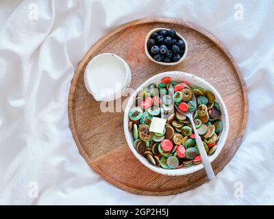 Plats tendance - céréales à crêpes. Bol de mini crêpes aux céréales colorées sur plateau en bois au-dessus du lit. Petites crêpes aux couleurs naturelles - matcha vert, dinde Banque D'Images