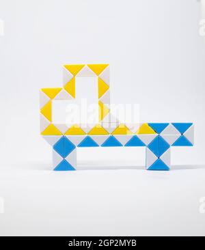 Jouet de camion fait de triangles bleus, jaunes et blancs sur fond blanc. Banque D'Images
