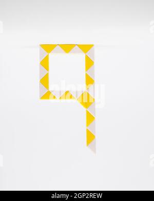 Lettre « q » composée de triangles jaunes et blancs sur fond blanc. Banque D'Images