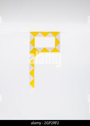 Lettre 'p' composée de triangles jaunes et blancs sur fond blanc. Banque D'Images