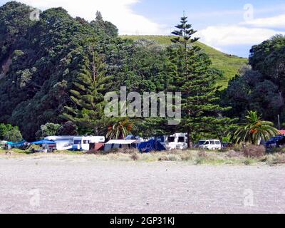 Les camping-cars et les tentes sur la plage le long de la rive est de l'île du Nord en Nouvelle-Zélande pendant les vacances de Noël est une tradition de vacances.Le camping à Noël est une tradition Kiwi soutenue par la capacité de camper librement dans tout le pays, connu comme le camping de liberté. Banque D'Images