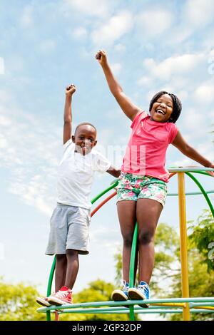 Portrait complet de deux enfants africains criant et levant les mains dans le parc. Banque D'Images