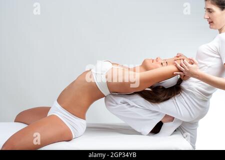 Close up of physiothérapeute massage stretching manipulatrice faisant le jeune femme. Couple avec retour sur thérapeute genou. Banque D'Images