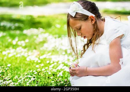 Gros plan portrait d'une jolie fille en robe blanche cueillant des fleurs. Banque D'Images