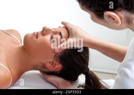 Close up d'ostéopathe traitement de guérison faire sur la tête de femme. Ce faisant mains massage sur l'avant et l'arrière de la tête. Banque D'Images