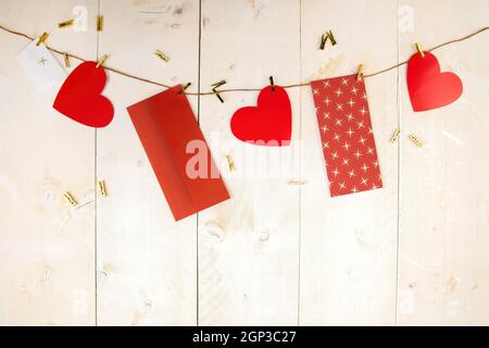 Coeurs rouges et enveloppes accrochés au cordon sur fond en bois. Cartes postales avec symboles d'amour sur bois blanc avec espace de copie. Toile de fond horizontale avec val Banque D'Images