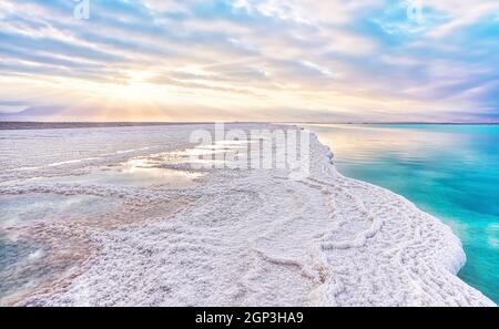 Le soleil du matin brille sur des formations de cristaux de sel, clair vert cyan eau calme près, paysage typique à la plage d'Ein Bokek, Israël. Banque D'Images