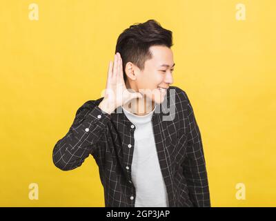 jeune homme souriant, main sur l'oreille, écoutant une audition rumeurs ou potins Banque D'Images