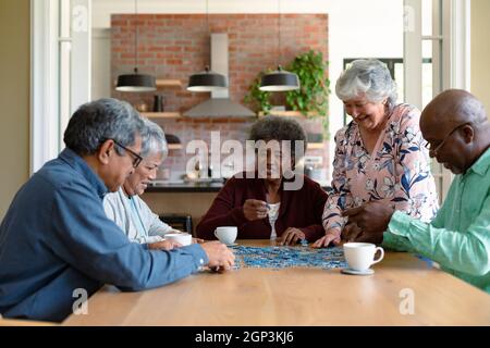 Groupe d'amis hommes et femmes âgés divers faisant des puzzles à la maison Banque D'Images