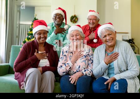 Groupe de heureux divers groupe d'amis seniors à santa Hats ayant la vidéo d'appel à l'heure de noël Banque D'Images