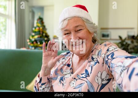 Bonne femme caucasienne âgée portant un chapeau de père noël ayant un appel vidéo à l'heure de noël Banque D'Images