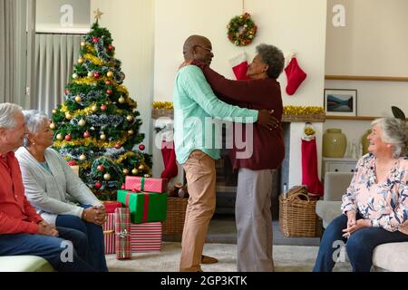 Couple afro-américain de haut niveau dansant devant divers amis masculins et féminins à l'heure de noël Banque D'Images