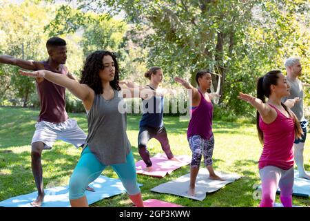 Groupe de diverses femmes et hommes pratiquant le yoga à l'extérieur Banque D'Images
