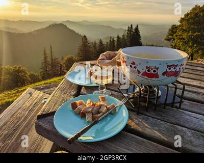 Fondue sur le Schnebelhorn. Cuisine suisse traditionnelle avec fromage au coucher du soleil sur la colline de Zurich. Dîner vin blanc Banque D'Images