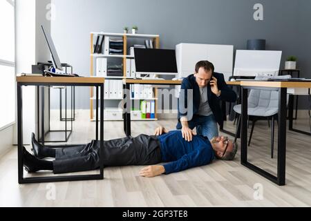 Aider un homme âgé évanoui dans le bureau après avoir déraillé et Automne Banque D'Images