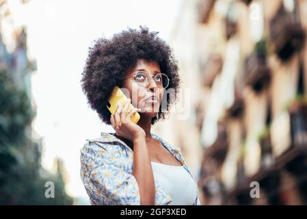 Jeune femme africaine à la mode qui parle par téléphone dans les rues de Barcelone Banque D'Images