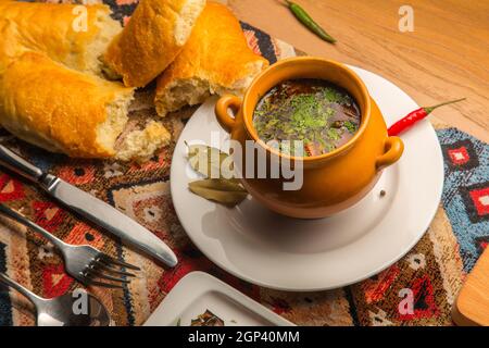 Soupe chaude et épicée et bouillon de poulet aux herbes et aux épices dans un pot en argile. Plat national géorgien fait maison. Concept - menu pour un restaurant Banque D'Images