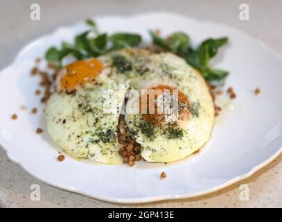 Œuf frit avec sarrasin et arugula sur une assiette blanche Banque D'Images