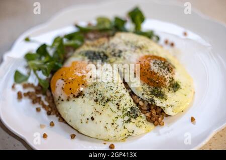 Œuf frit avec sarrasin et arugula sur une assiette blanche Banque D'Images