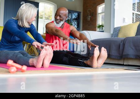 Heureux senior divers couple en vêtements d'exercice pratiquant le yoga ensemble, étirant Banque D'Images