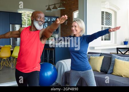 Heureux senior divers couple en vêtements d'exercice pratiquant le yoga ensemble, étirant Banque D'Images