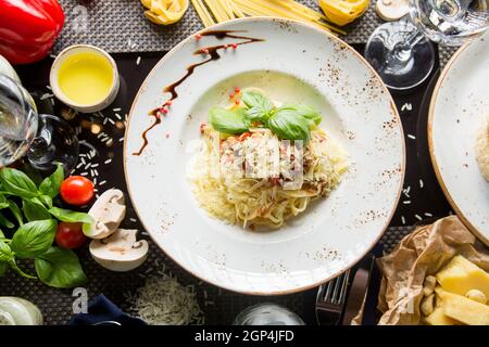 Pâtes italiennes au parmesan, sauce crémeuse et bacon. Spaghetti dans une assiette avec des herbes. Concept - nourriture, délices. Banque D'Images