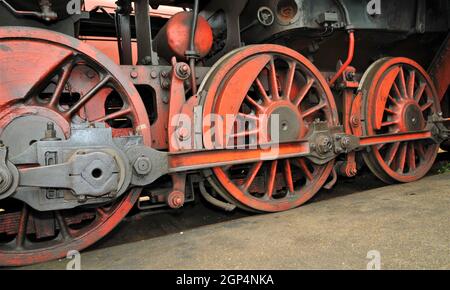 Vieilles roues de train rouges d'une vieille locomotive à vapeur dans le dépôt industriel et d'époque du chemin de fer Banque D'Images