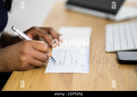 Une femme africaine signant un chèque de banque ou un chèque de paie Banque D'Images